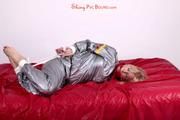 Pia tied and gagged in a shiny silver sauna suit bare feet on a bed (Pics)