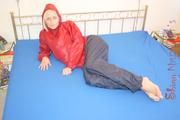 Sabrina dressing on bed and posing wearing a supersexy darkblue adidas shiny nylon pants and an oldschool red rain jacket (Pics)