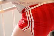 Jill tied and gagged standing on a stairway wearing a sexy red adidas shiny nylon shorts and a top (Pics)