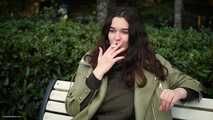 Young brunette is taking an unhurried stroll with allwhite 120mm cigarette