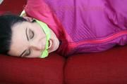 Jill tied and gagged on a red sofa wearing a sexy pink down combination (Pics)