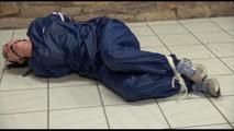 Jill tied and gagged on the floor in an old cellar wearing a shiny blue PVC sauna suit (Video)