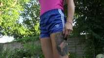 Watch Maly in her shiny nylon Shorts enjoying the warm Weather in the Garden