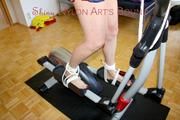 Pia tied and gagged on a crosstrainer for doing her workout right wearing a sexy blue shiny nylon shorts and an oldschool rain jacket (Pics)