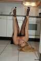 Pierced MILF Nina poses in a black dress, stockings and heels in the kitchen