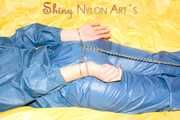 Alina wearing a sexy shiny rainwear suit in blue lolling on bed cuffed (Pics)