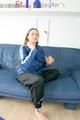 Katharina posing on a sofa wearing a blue/black shiny nylon rainwear (Pics)