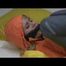 Samantha tied and gagged in bed wearing an orange/grey shiny nylon rainwear combination (Video)