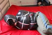 Jill tied, gagged and hooded on a bed wearing a grey rain pants and a black downjacket with closed zip for breath control play (Pics)