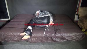 Watching sexy Sandra being tied and gagged on a bed with ropes and a ballgag wearing a supersexy shiny black nylon pants and a silver down jacket (Video)