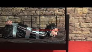 Mara tied with tape and gagged on a princess bed in an old cellar wearing an black sauna suit (Video)