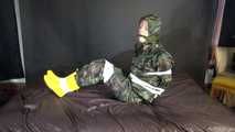 Watching sexy Pia being tied and gagged with tape on a bed wearing a sexy camouflage shiny nylon rainpants and a rainjacket as well as yellow rubber boots (Video)