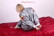 Pia tied and gagged in a shiny silver sauna suit bare feet on a bed (Pics)