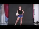 Brown-haired archive girl posing with an soccer ball wearing shiny nylon shorts and a rain jacket (Video)