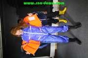 Stella helps Ronja to pullover a lifevest the other way round both wearing shiny nylon downwear (Pics)