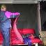 Watching Pia wearing a blue/purple/pink shiny nylon rain suit folding clothes and tidying up the studio (Video)
