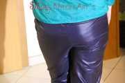 Mara wearing a blue rain pants and a green rain jacket posing infront of a mirror (Pics)