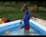 Mara in the swimming pool wearing a sexy red shiny nylon shorts and a lightblue sihny rain jacket playing with the water (Video)