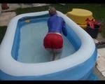 Mara in the swimming pool wearing a sexy red shiny nylon shorts and a lightblue sihny rain jacket playing with the water (Video)