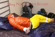 Pia tied and gagged on bed wearing a yellow rain pants and an orange downjacket (Pics)