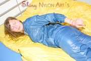 Alina wearing a sexy shiny rainwear suit in blue lolling on bed cuffed (Pics)