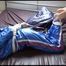 Mara tied and gagged on bed wearing s shiny blue PVC sauna suit (Video)