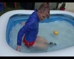 Mara in the swimming pool wearing a sexy red shiny nylon shorts and a lightblue sihny rain jacket playing with the water (Video)
