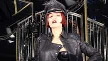 Mistress Tokyo smoking cigarette in leather, gloves and Muir Cap; fetish, POV