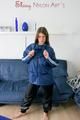 Katharina posing on a sofa wearing a blue/black shiny nylon rainwear (Pics)