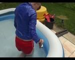 Mara in the swimming pool wearing a sexy red shiny nylon shorts and a lightblue sihny rain jacket playing with the water (Video)