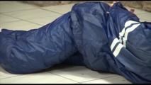 Jill tied and gagged on the floor in an old cellar wearing a shiny blue PVC sauna suit (Video)