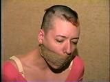 PUNK GIRL MELA IS WRAP TAPE GAGGED, BAREFOOT, TOE-TIED & BALL-TIED ON THE BED (D46-15)