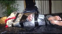 Pia tied and gagged with tape and gag on bed wearing a sexy silver shiny rainwear suit (Video) 