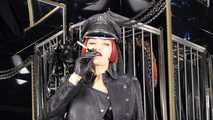 Mistress Tokyo smoking cigarette in leather, gloves and Muir Cap; fetish, POV