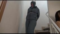 Jill tied, gagged and hooded in an stairway wearing a sexy shiny grey downwear (Video)