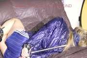 ***HOT SANDRA*** wearing a supersexy blue shiny nylon shorts and a transparent blue rain jacket tied and gagged on a sofa with a bar and a cloth gag (Pics)