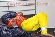Pia tied and gagged on bed wearing a yellow rain pants and an orange downjacket (Pics)