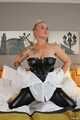 Blonde Frida posiert in Ledercorsage und Glanz-Leggins auf dem Bett