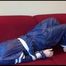 Mara tied and gagged on a sofa wearing a shiny blue PVC sauna suit (Video)
