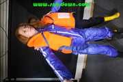 Stella helps Ronja to pullover a lifevest the other way round both wearing shiny nylon downwear (Pics)