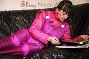 Watching sexy Mara lying on a black shiny sofa wearing a sexy pink downsuit reading a book (Pics)