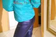 Mara wearing a blue rain pants and a green rain jacket posing infront of a mirror (Pics)