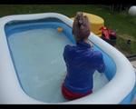 Mara in the swimming pool wearing a sexy red shiny nylon shorts and a lightblue sihny rain jacket playing with the water (Video)