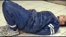 Jill tied and gagged on the floor in an old cellar wearing a shiny blue PVC sauna suit (Video)