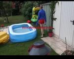 Mara in the swimming pool wearing a sexy red shiny nylon shorts and a lightblue sihny rain jacket playing with the water (Video)