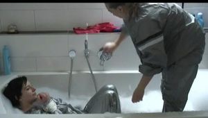 Simone  with an shiny silver PVC sauna suit tied and gagged by Sophie in an bath tub (Video)