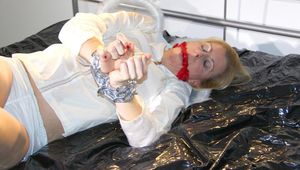 Pia tied and gagged on a bed with cuffs wearing a sexy white shiny nylon shorts and a rain jacket as well as wings (Pics)