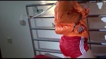 Sonja wearing a sexy super small red shiny nylon shorts and an orange rain jacket tied on bed with neckband and cuffs, gagged with a ball in a cloth (Video)
