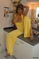 Busty Alexandra posing in a yellow jumbsuit in the kitchen