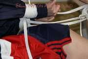 Sexy Pia being tied and gagged on a sofa with ropes and a cloth gag wearing a sexy darkblue shiny nylon shorts and a blue/red rain jacket (Pics)